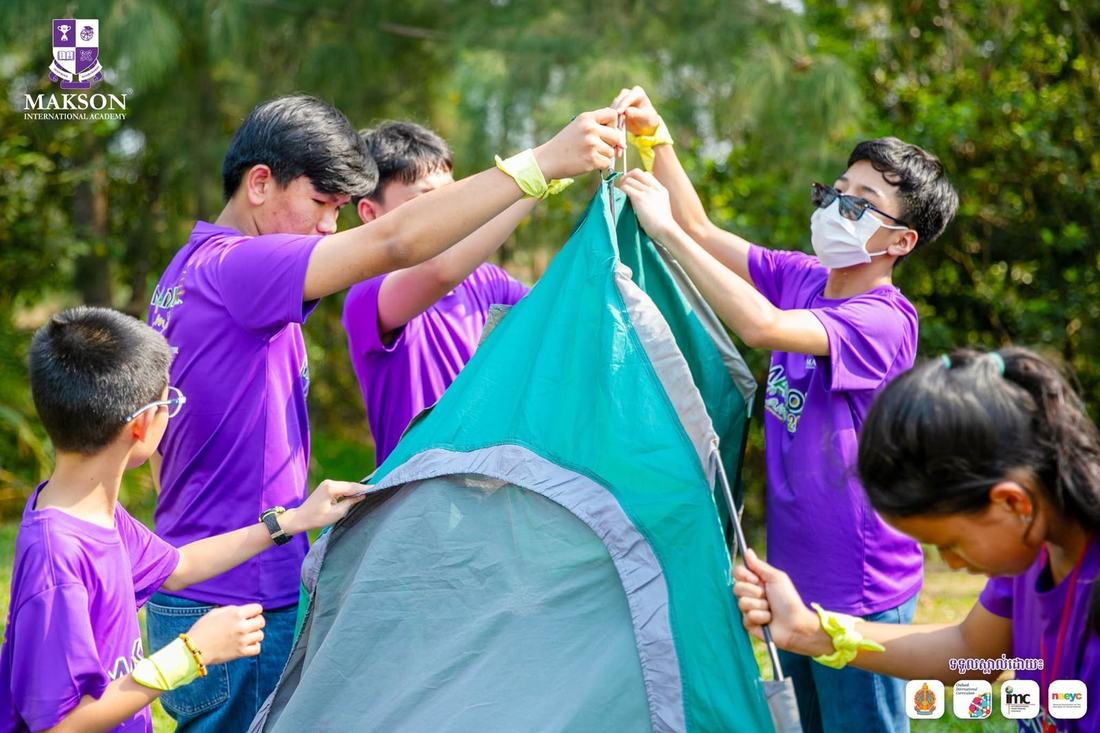 Students working together to pitch a tent